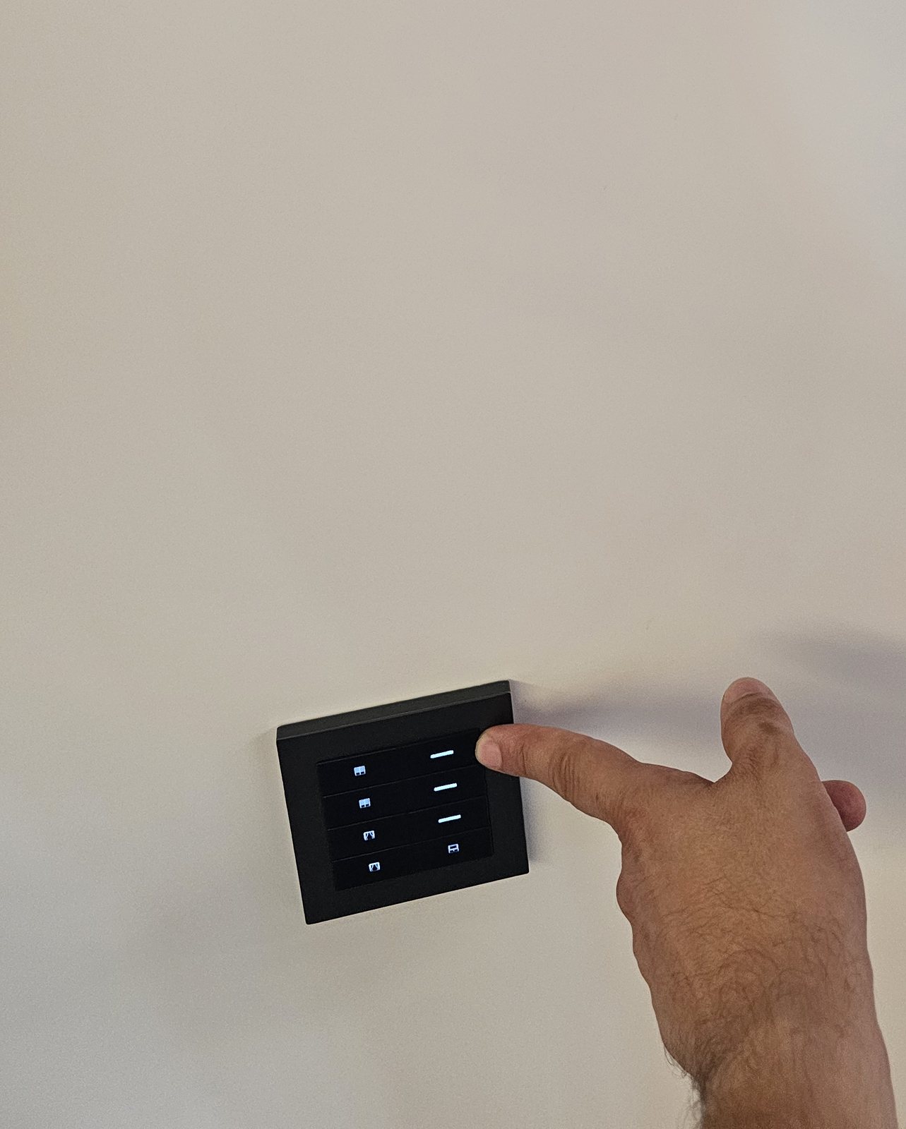 Pulsantiera KNX a otto tasti a parete, premuta da una mano