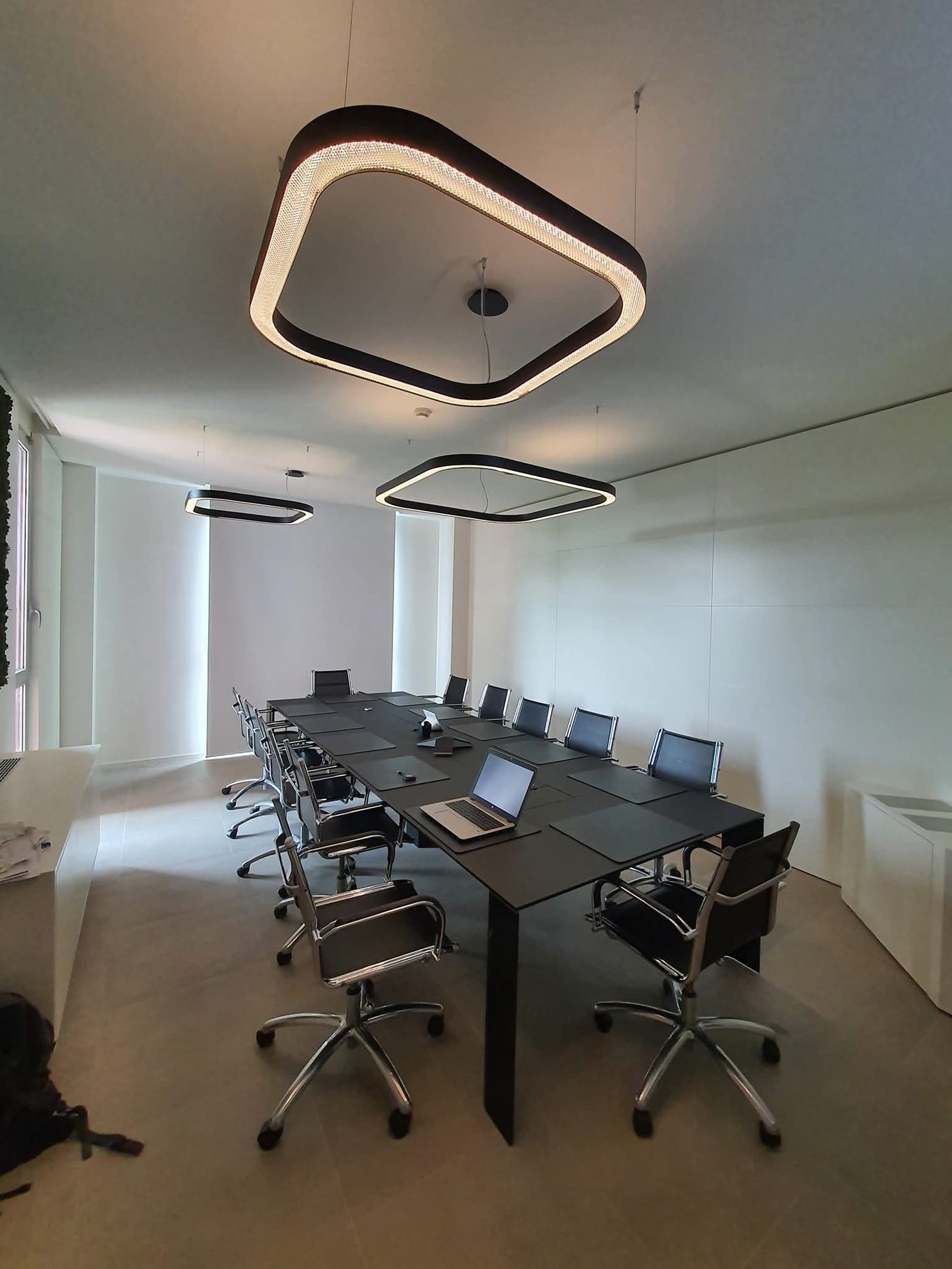 Sala riunioni con tavolo lungo e tre lampade a sospensione ad anello